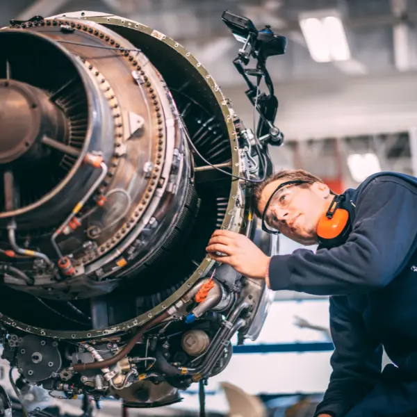 Aircraft engineer repairing and maintaining an airplane's jet engine in a maintenance hangar